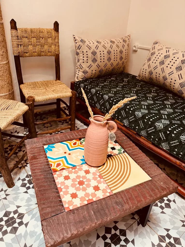 Surf camp lounge Essaouira low coffee table patterned ceramic tiles straw chairs geometric sofa cushions Moroccan floor tiles